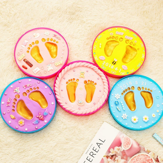 A vibrant set of baby hand and foot print mud or clay kits, designed for newborns, displayed with colorful plaques and decorative elements. Perfect for creating lasting keepsakes, this product is available exclusively on Giggly Groves Toy Website.