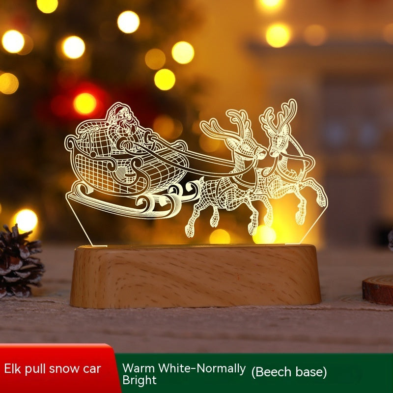 Illuminated Christmas LED lamps with a 'Merry Christmas' sign featuring reindeer antlers and a Christmas tree with presents underneath. The lamps glow warmly, set against a backdrop of a decorated Christmas tree with lights and ornaments. Pine branches and a pine cone add to the festive ambiance.
