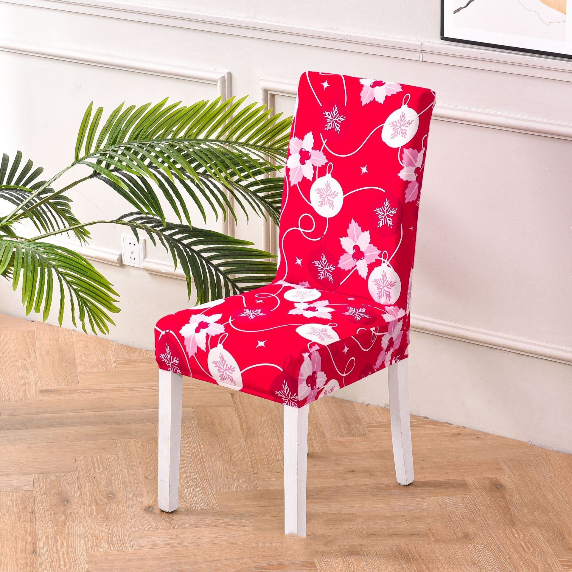 A sleek dining chair with a festive red fabric cover, adorned with Christmas-themed white patterns, including reindeer, snowflakes, and stars. The chair has white legs and is placed against a plain white background, creating a clean and minimalistic holiday decor setting.