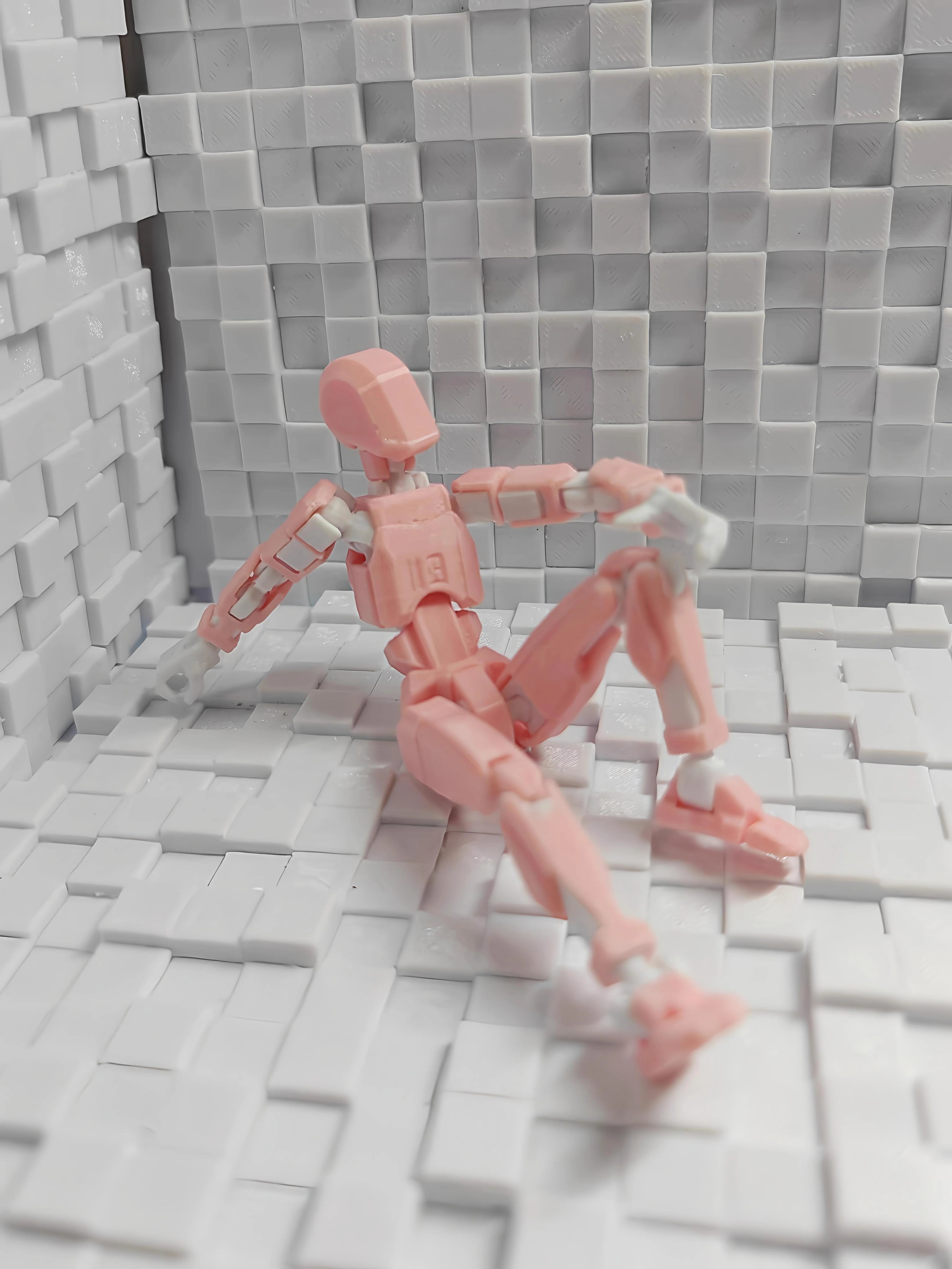 A pink plastic articulated action figure posed sitting on a white tiled surface against a matching white tiled wall background.