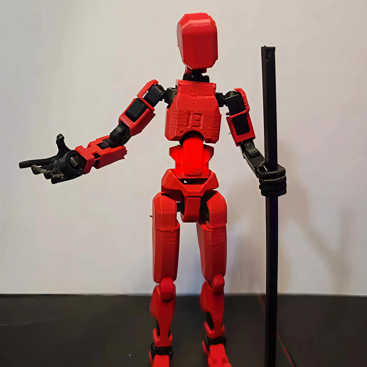 Red robot figure on a stand against a white background