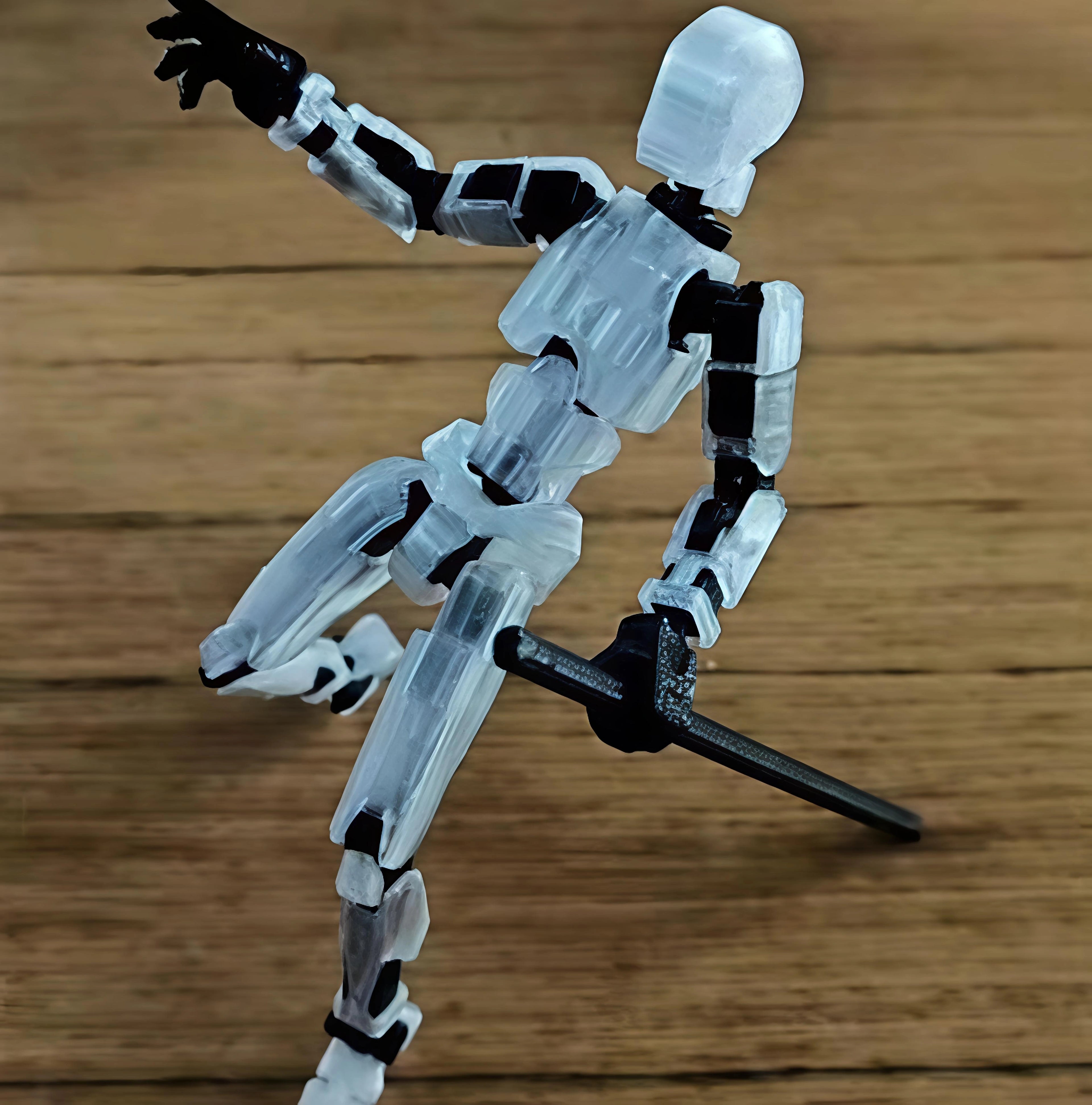 A translucent acrylic articulated model of a human figure holding a black sword, posed dynamically on a wooden surface.