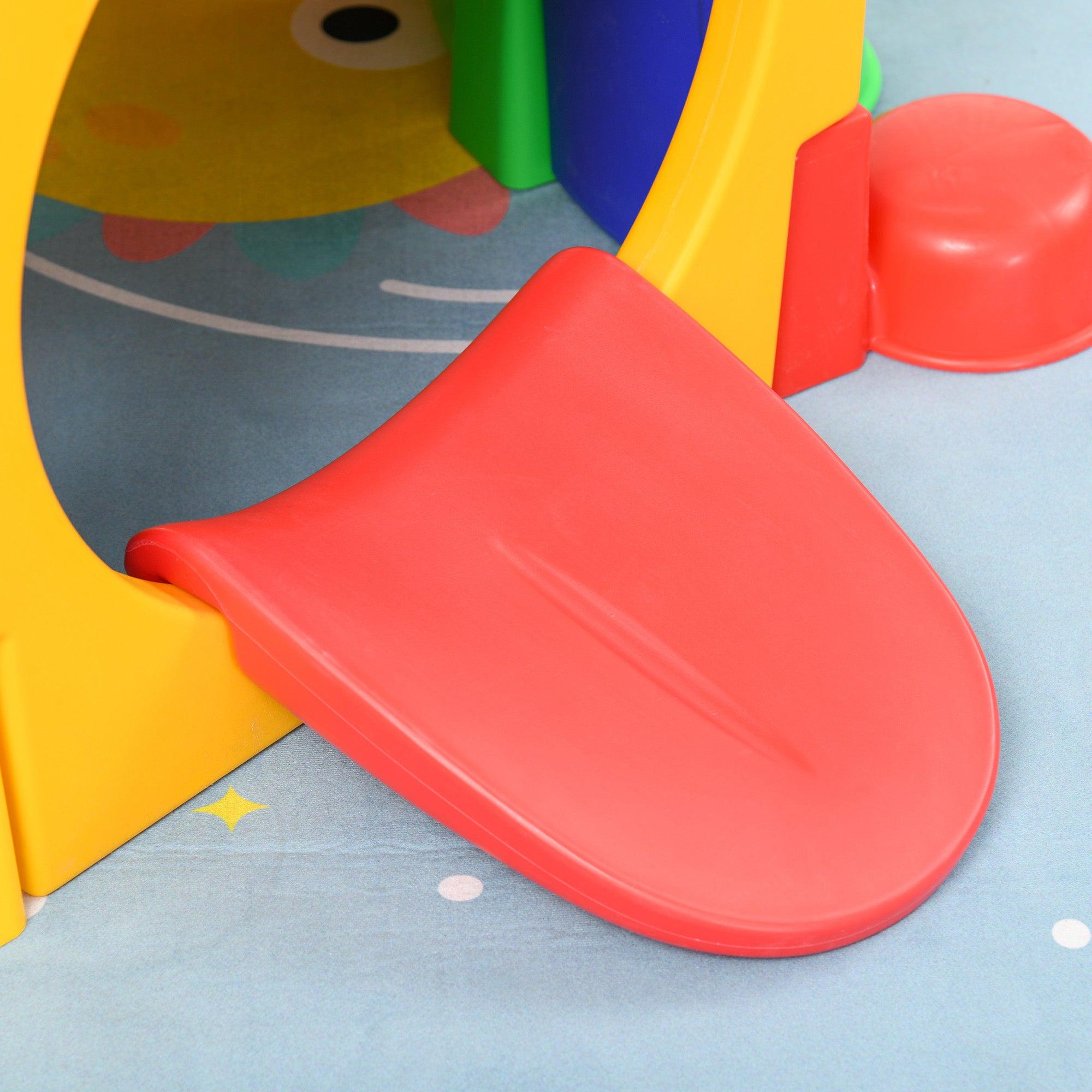 Close-up detail of the bright red tongue-shaped entry ramp of the caterpillar tunnel, showcasing the smooth, durable HDPE plastic material.